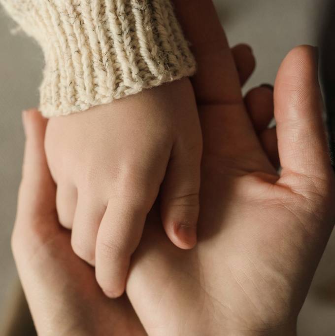 La main d'un tout-petit posée dans la main ouverte d'un adulte